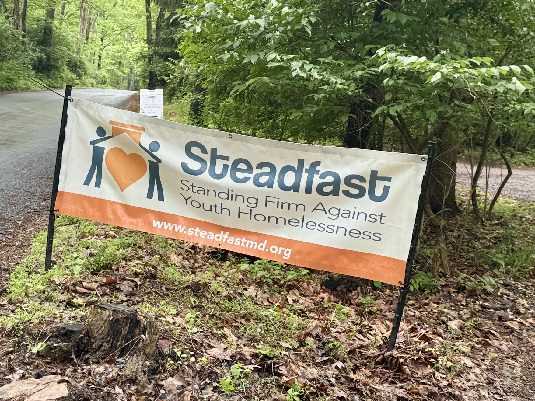 Orange and teal Steadfast banner anchored with stakes in the ground