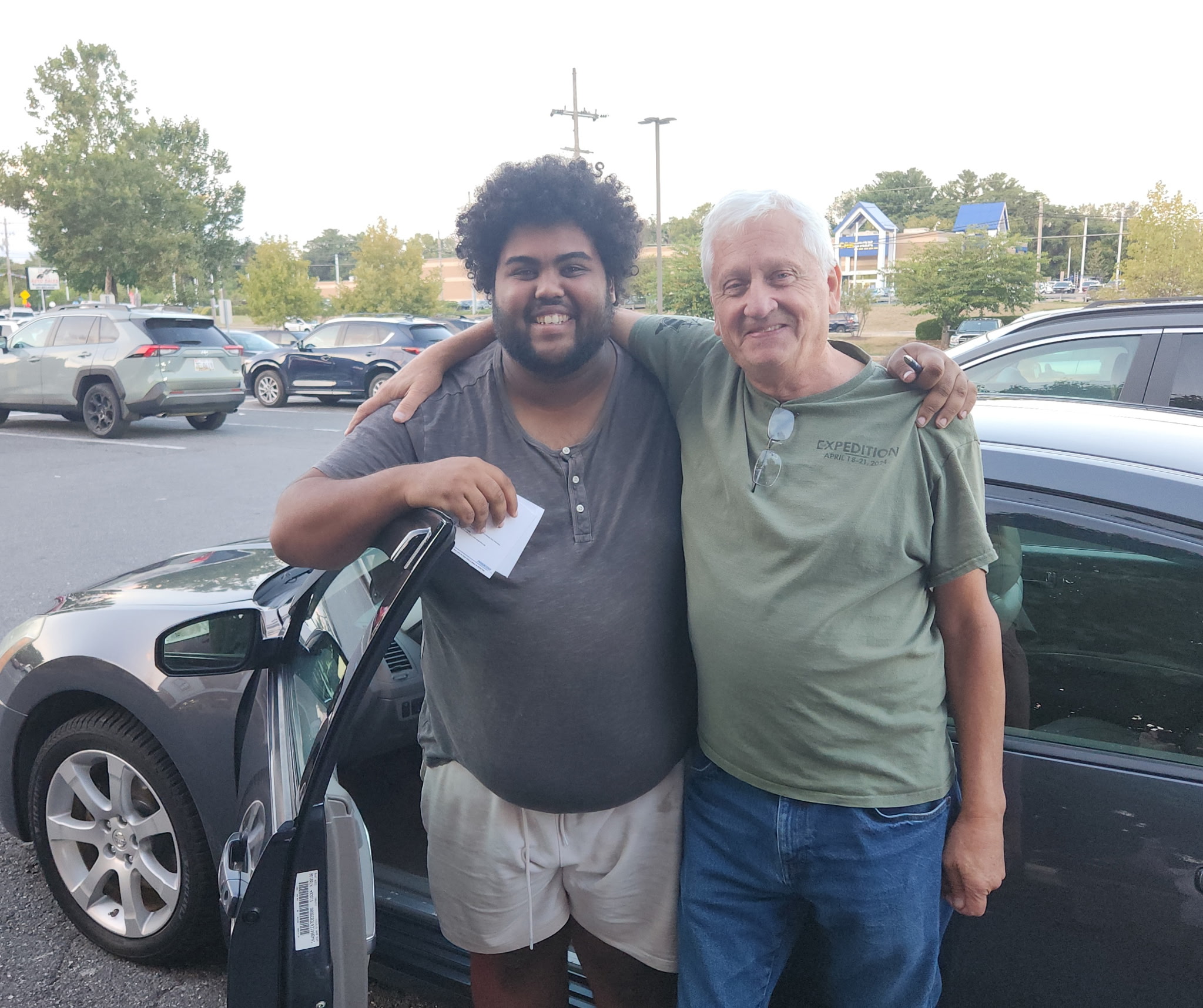 one of Steadfast's youth arm and arm with older man as he receives the keys to a donated dark blue car