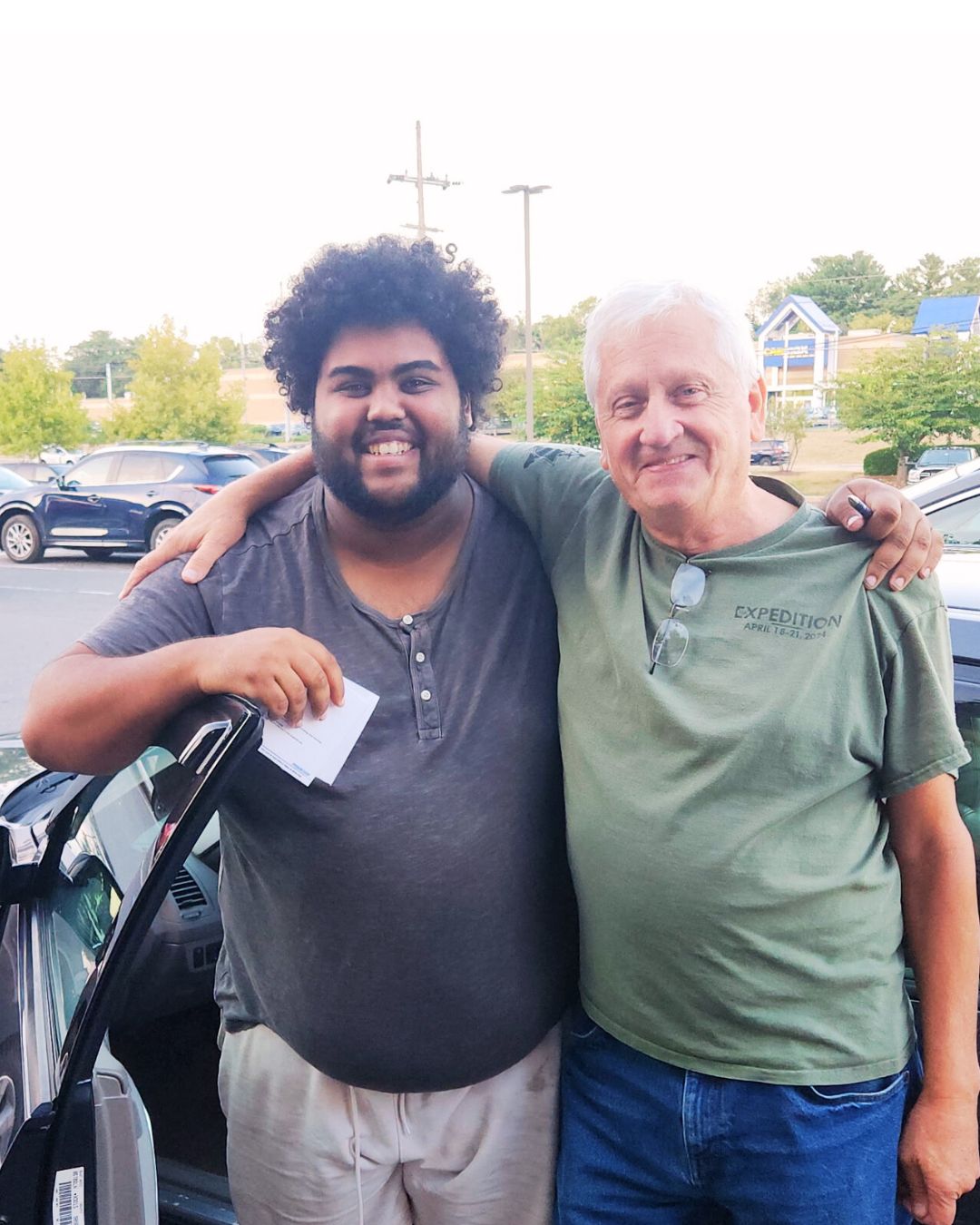 one of Steadfast's youth arm and arm with older man as he receives the keys to a donated car