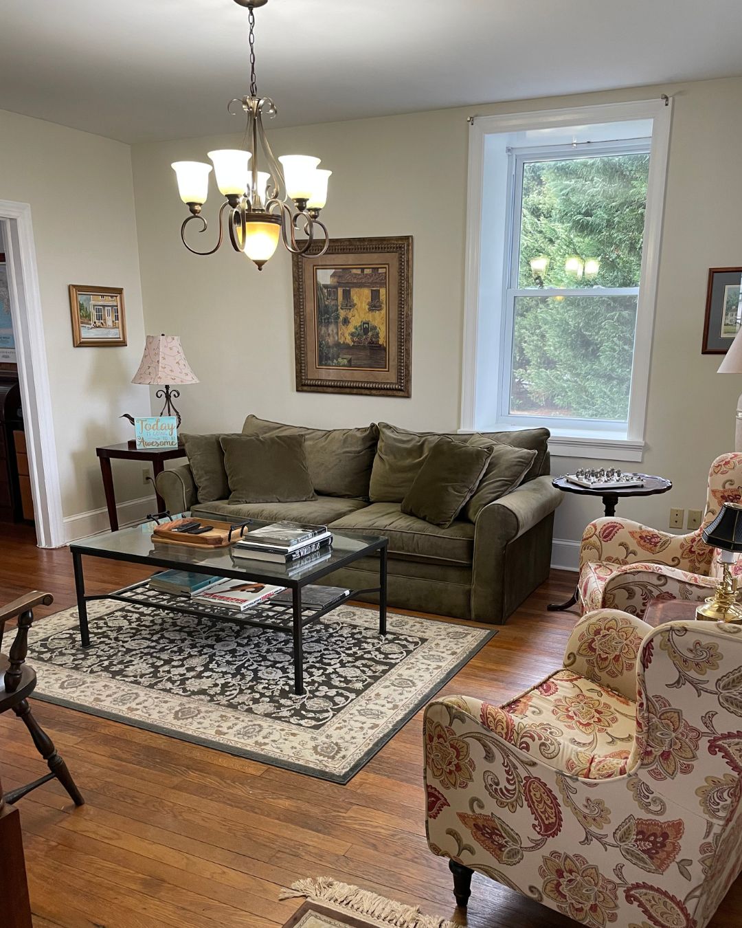 color photo of Steadfast living room with green sofa, area rug and glass coffee table, two side chairs, wooden flooring
